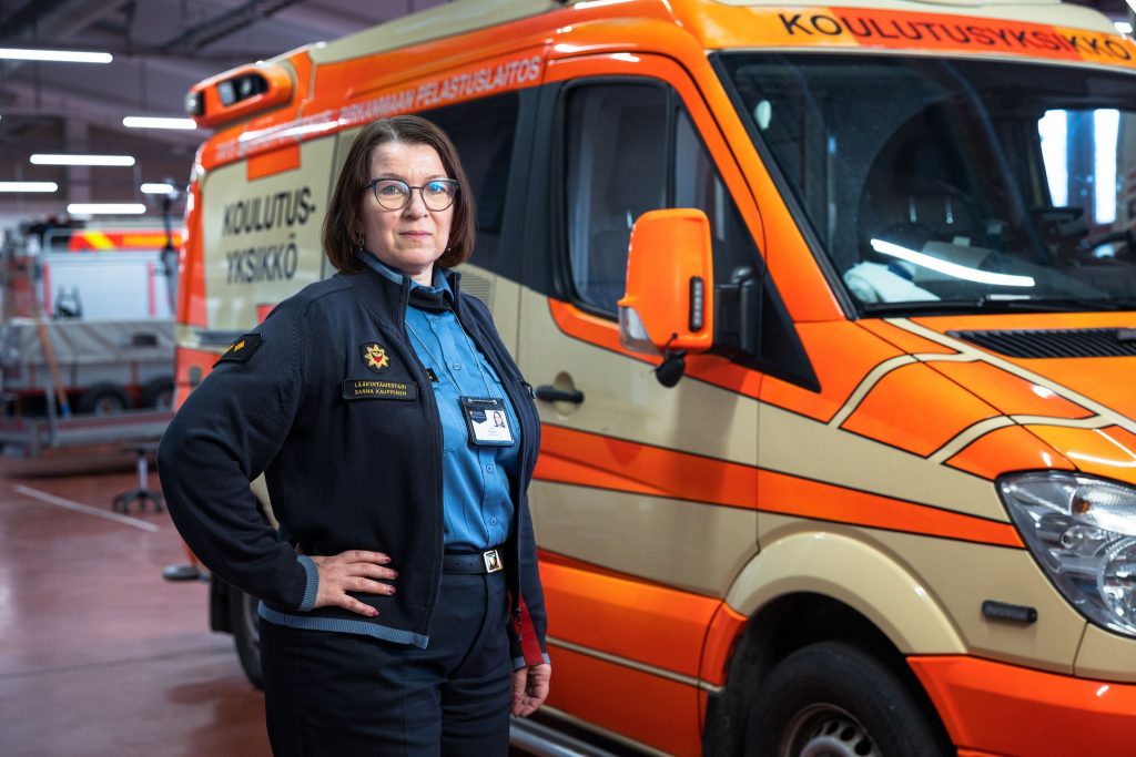 Lääkintämestari Sanna Kauppinen seisoo ambulanssin vierellä.