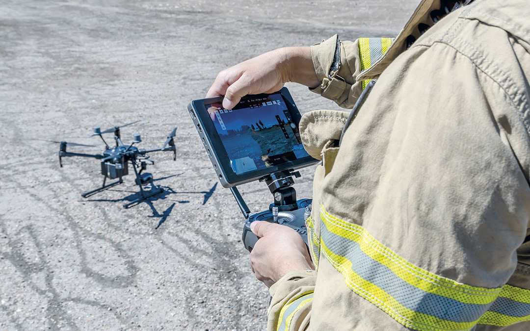 Drone sekä palomies, joka käyttää dronen ohjainta.